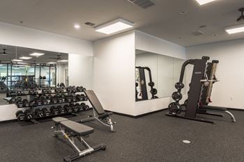 A spacious fitness room with free weights and mirrors